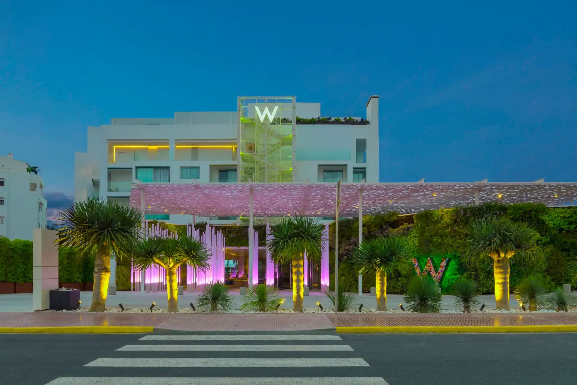 Stylischer Hoteleingang des W Ibiza mit moderner Architektur, farbenfroher LED-Beleuchtung und tropischem Flair inmitten der Stadt.