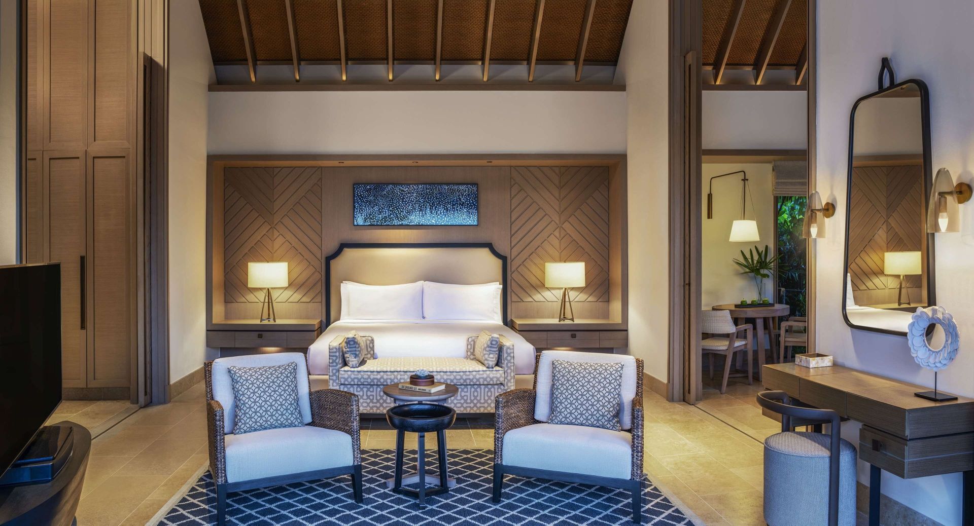 Geräumiges Schlafzimmer einer Villa mit großem Doppelbett, zwei Sesseln und Teppichboden.