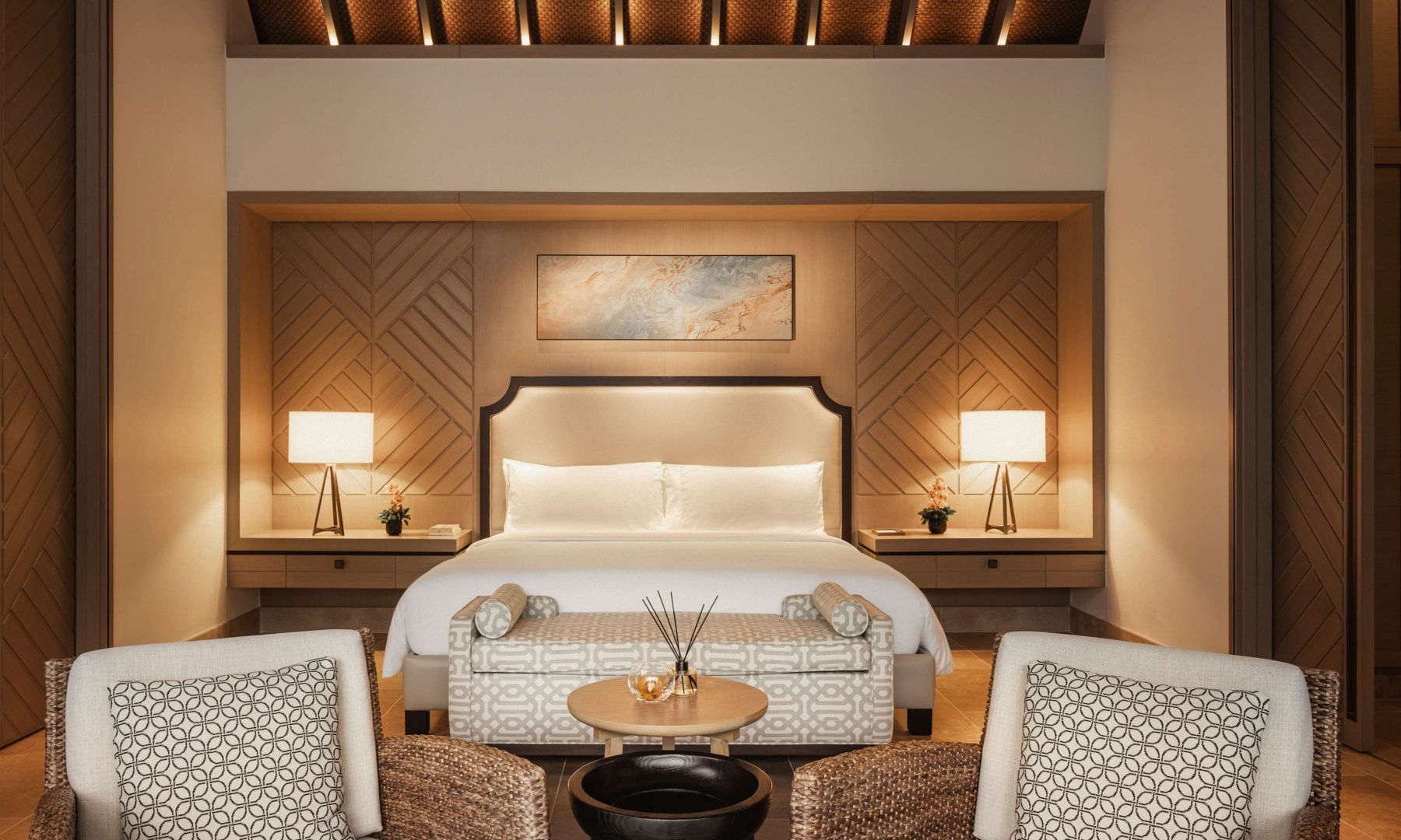 Schlafzimmer mit großem Doppelbett, Holzverkleidung und Sesselgruppe im Vordergrund.