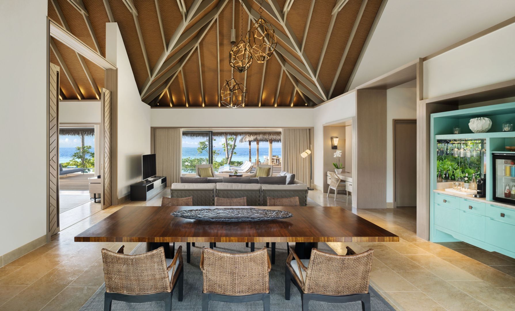 Offener Wohnbereich und Essbereich einer Villa mit großem Holztisch und Blick aufs Meer.