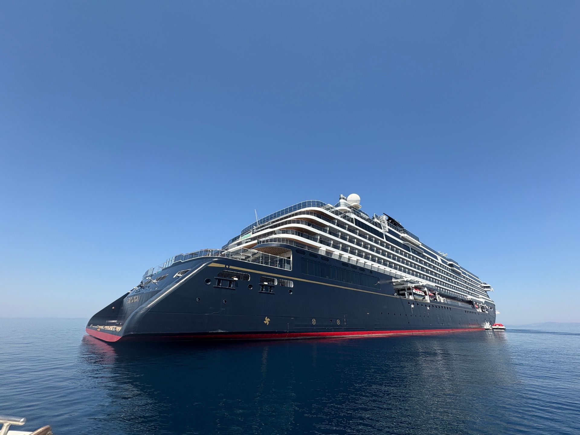 Majestätisches Kreuzfahrtschiff auf offenem Meer unter klarem blauen Himmel.
