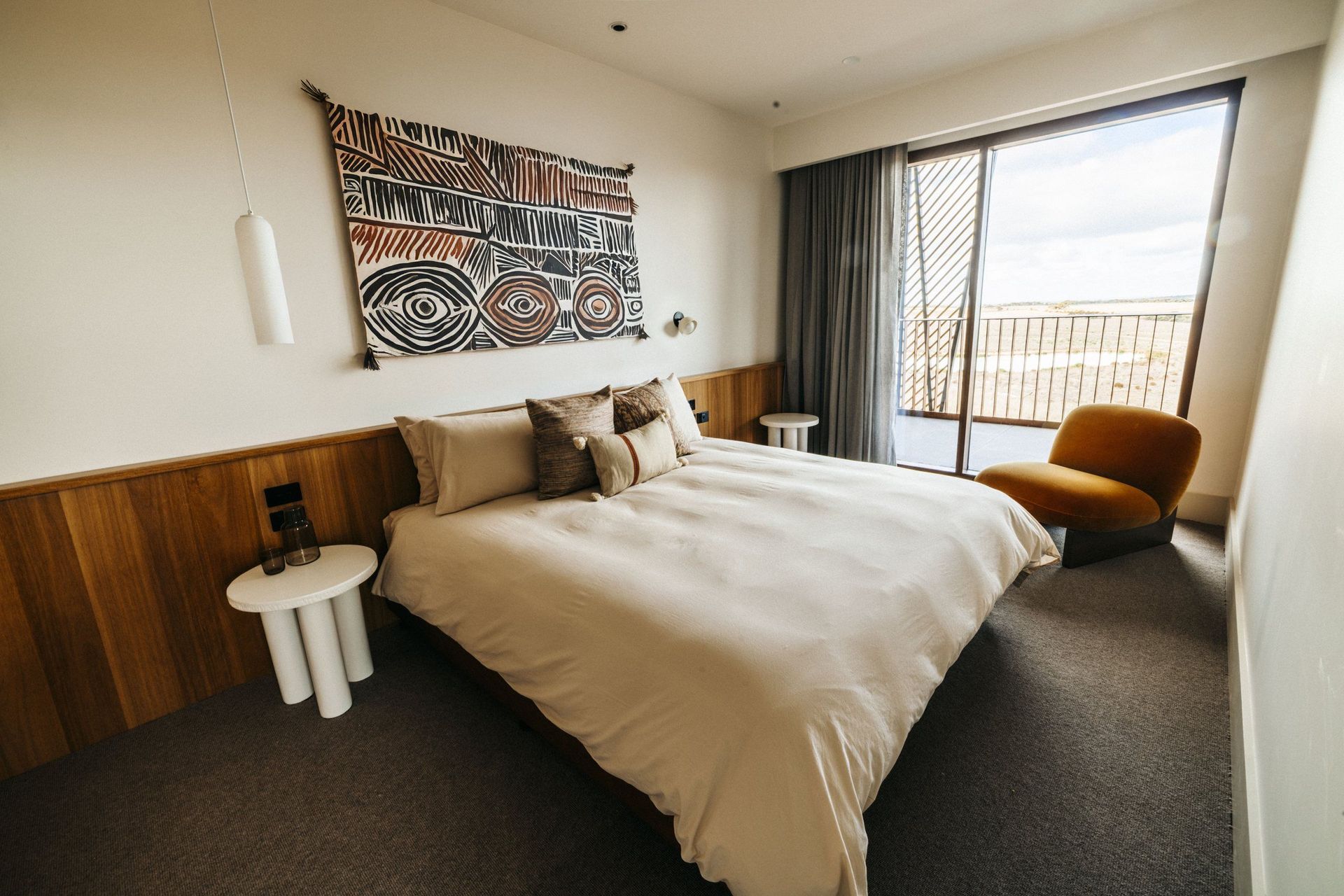 Hotelzimmer mit Doppelbett, großem gemustertem Wandbild und Fenster zum Balkon