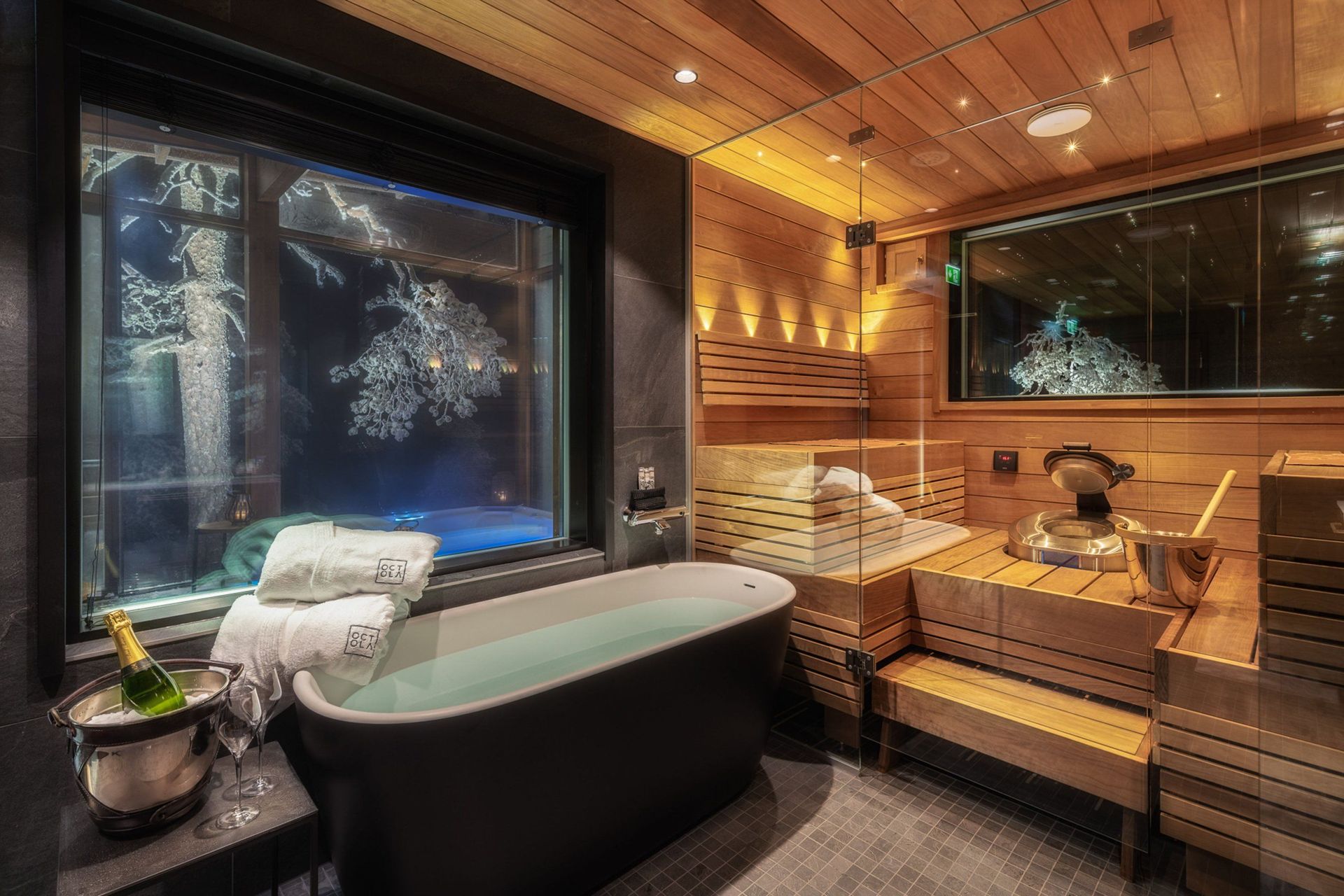 Bad der Octola Villa mit freistehender Wanne und verglaster Sauna, Fenster zur Winternacht