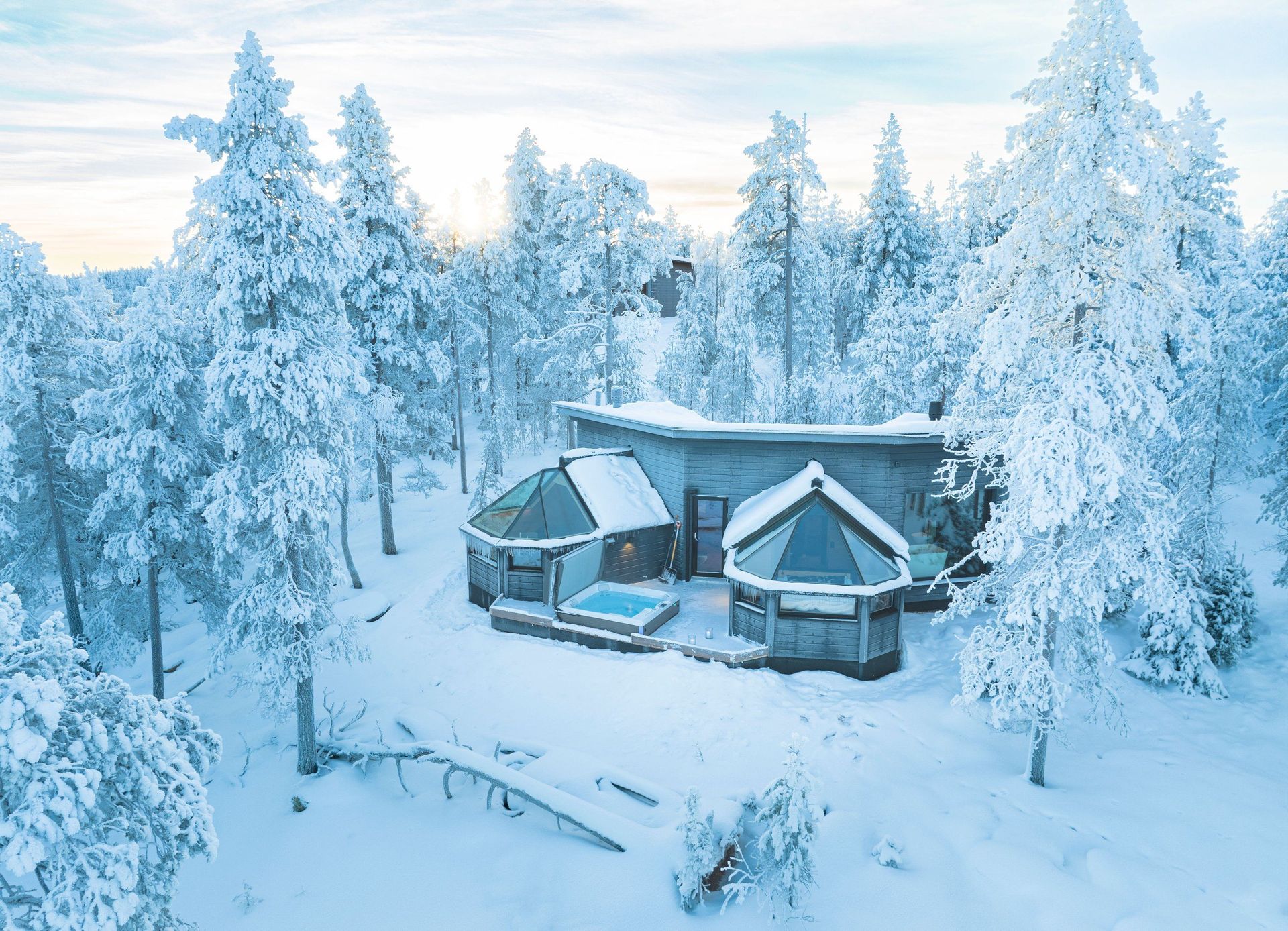 Luftbild der Glass Igloo Suite mit Glasdächern zwischen verschneiten Fichten