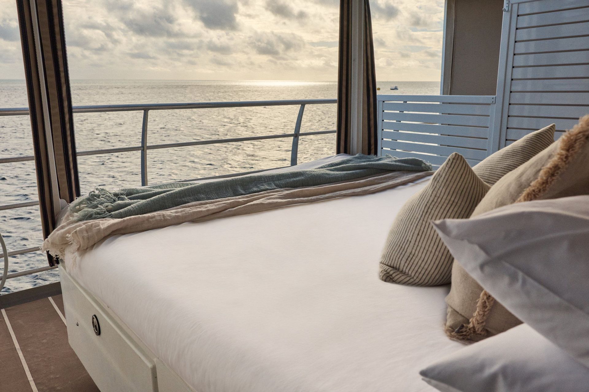 Reefsleep-Doppelbett mit Kissen unter dem Baldachin, dahinter Reling und offenes Meer