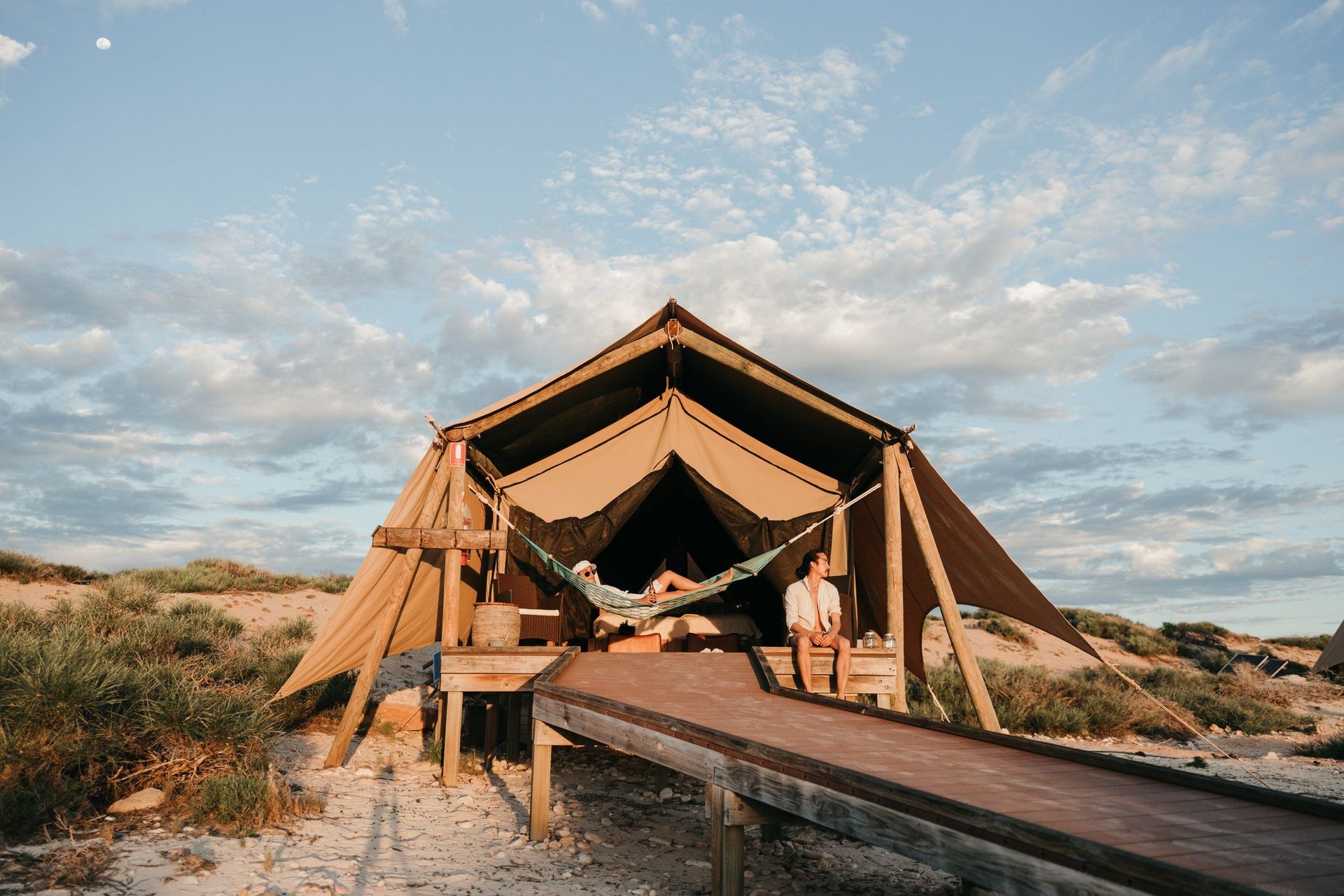 Wilderness Tent mit Hängematte auf dem Holzdeck, umgeben von Dünenvegetation