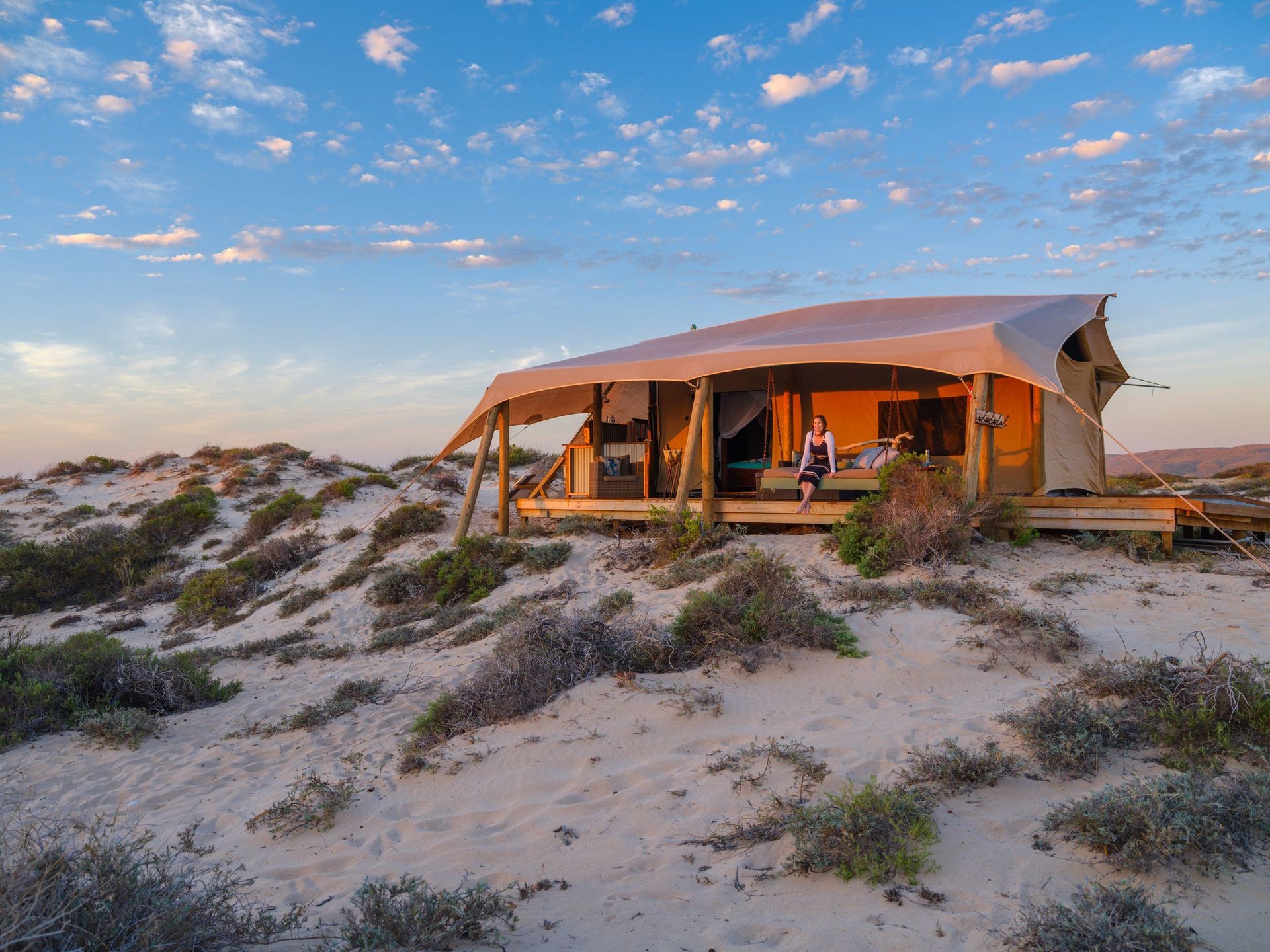 Honeymoon Tent mit großem Deck in den Dünen im warmen Abendlicht unter blauem Himmel