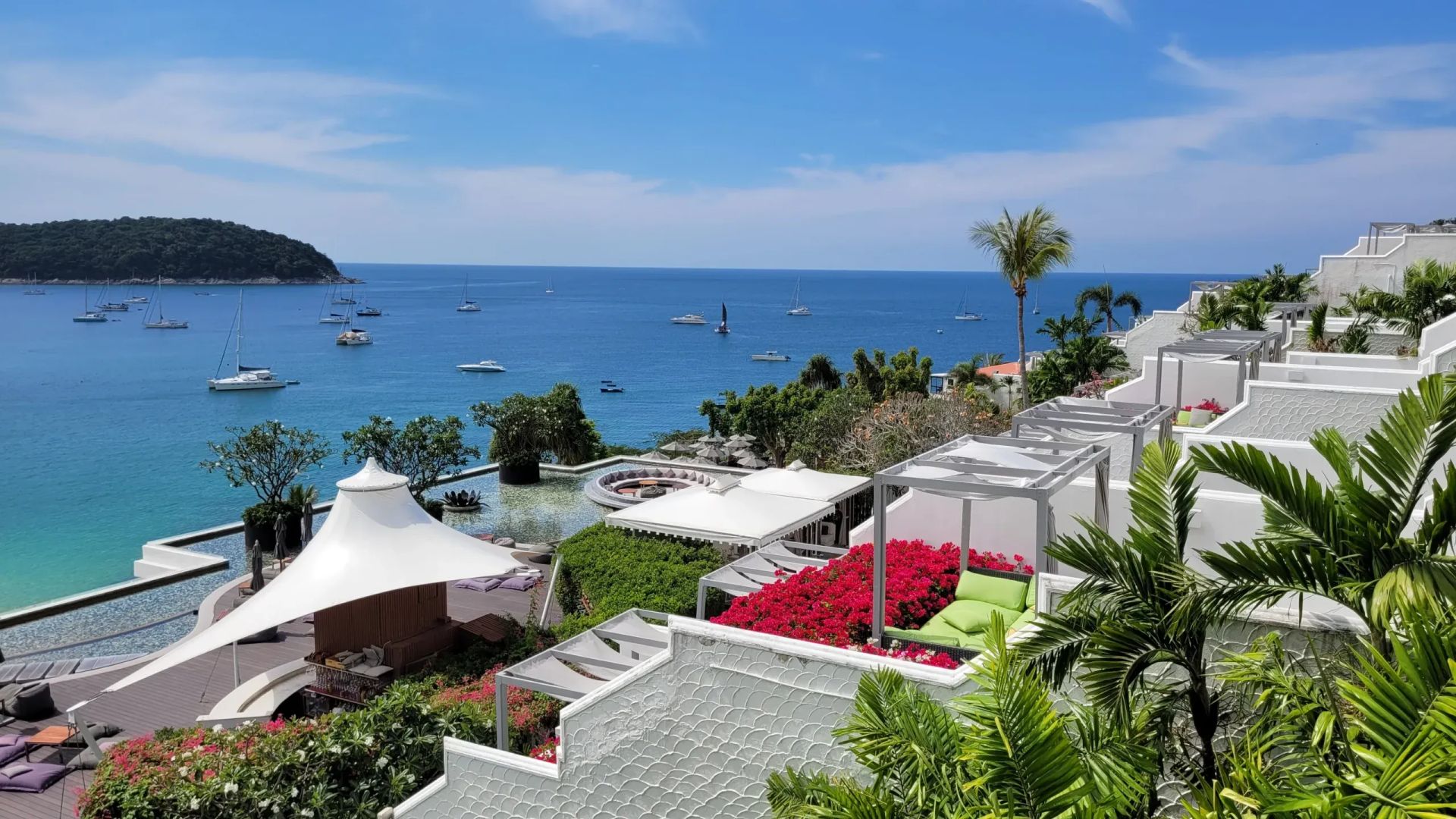 Panoramablick auf das Meer mit weißer Terrasse und Yachten bei sonnigem Himmel.