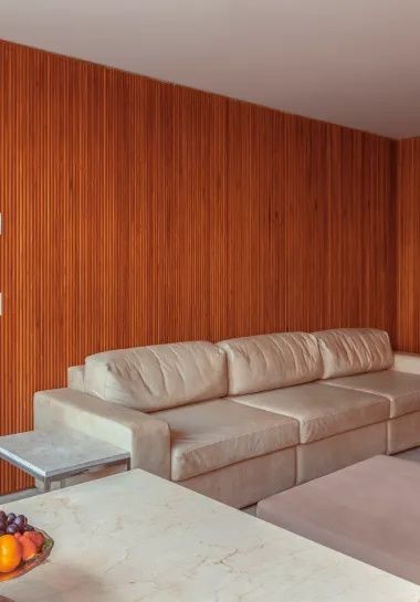 Helles Ledersofa vor einer Wand mit vertikaler Holzverkleidung im Hotelzimmer.