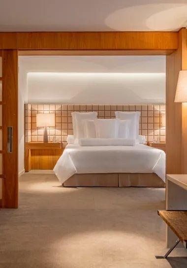 Schlafbereich einer Suite mit weiß bezogenem Bett und Nachttischlampen.