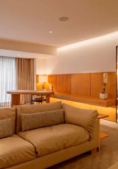 Wohnbereich mit beigefarbenem Sofa und langem Holzschreibtisch an der Wand.