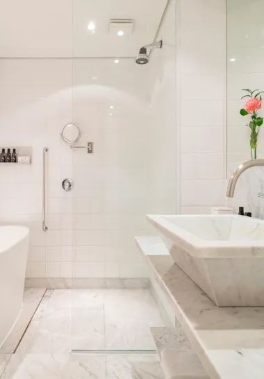 Weißes Badezimmer mit Marmorwaschbecken, Spiegel und Badewanne