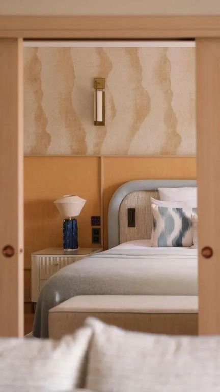 Komfortables Bett in einer Suite mit stilvoller Wandverkleidung und moderner Lampe.