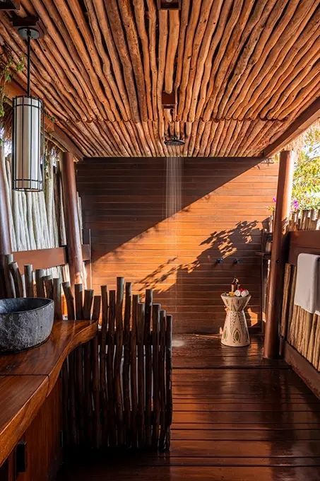 Naturbelassene Außendusche mit Holz und Stein, sanft beleuchtet durch Sonnenlicht