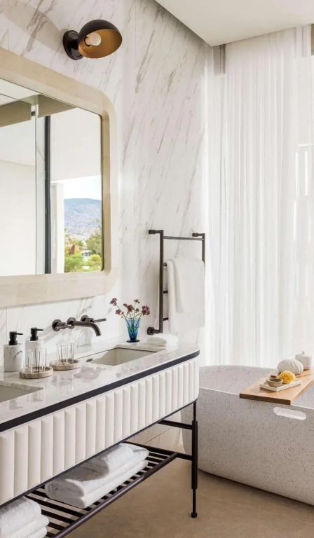 Luxuriöses Badezimmer mit Marmordetails und großen Spiegeln.