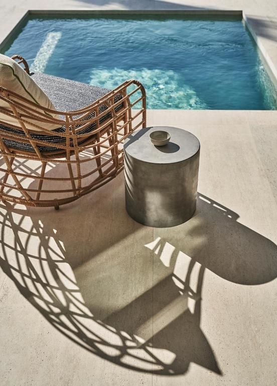 Flechtstuhl und kleiner Beistelltisch auf der Sonnenterrasse am Pool
