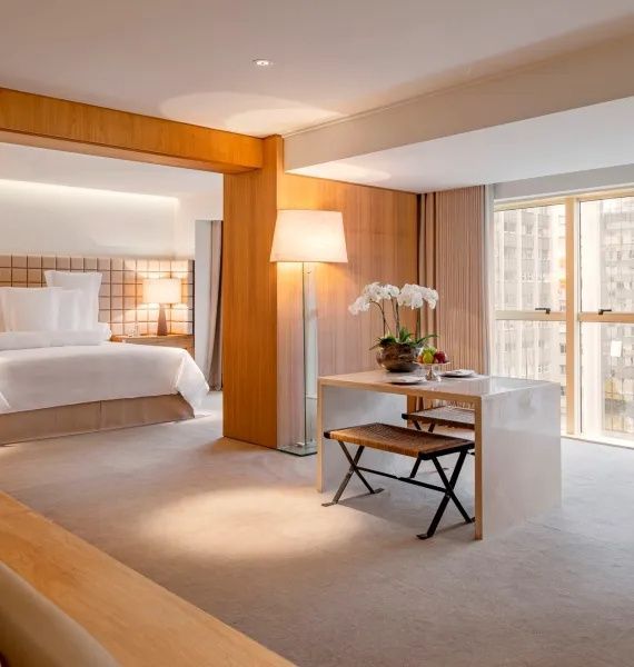 Helle Suite mit Doppelbett, Sitzbereich am Fenster und Holzverkleidung.