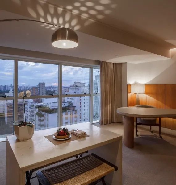 Sitzbereich im Zimmer mit Fensterfront und Blick auf die Stadtlandschaft.