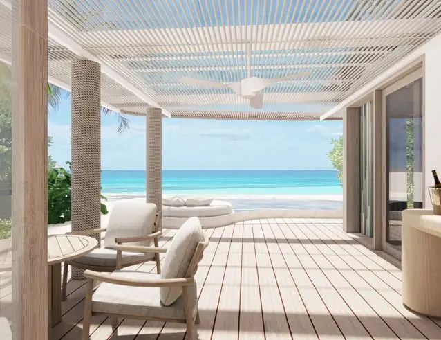 Überdachte Holzterrasse mit Sitzmöbeln und direktem Blick auf den Strand und das türkisfarbene Meer.