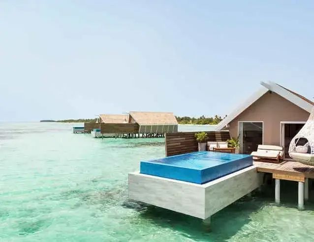 Privater Pool auf der Holzterrasse einer Wasservilla über dem türkisfarbenen Wasser.