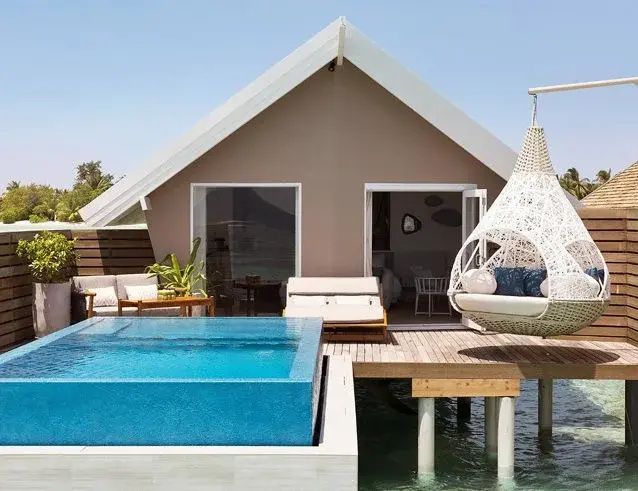 Außenansicht einer Wasservilla mit privatem Pool, Sonnenliegen und Hängesessel.