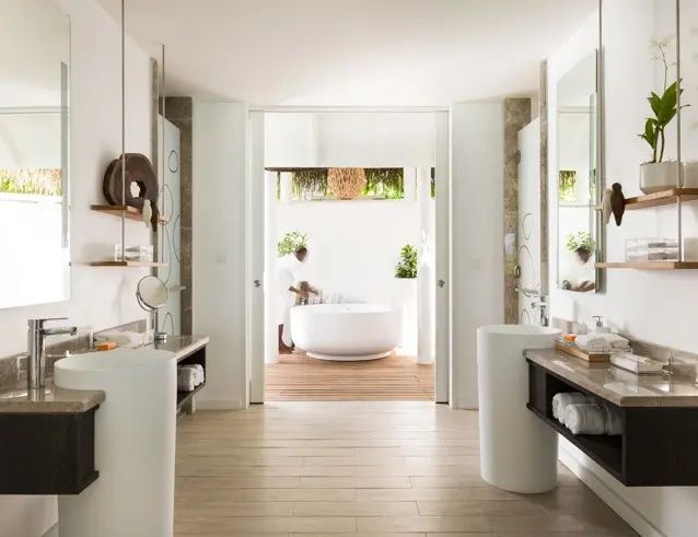Modernes Badezimmer mit zwei Waschtischen und Durchgang zu einer freistehenden Badewanne im Außenbereich.