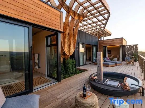 Moderne Holzarchitektur der Lodge mit weitläufiger Terrasse und integrierter Sitzgelegenheit.
