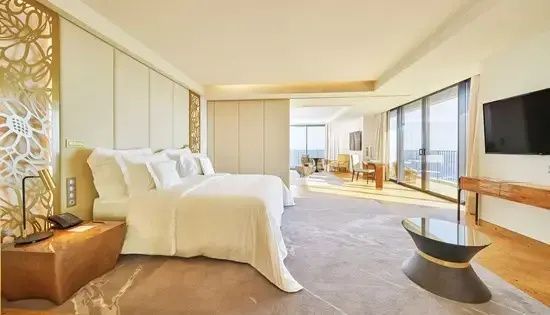 Großzügiges Hotelzimmer mit Doppelbett, Sitzbereich und bodentiefen Fenstern.