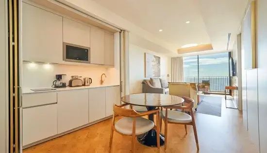 Wohnbereich einer Suite mit rundem Essplatz, Holzstühlen, Küchenzeile und Sofa.