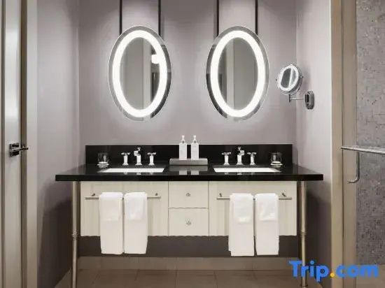 Waschtisch im Badezimmer mit zwei Waschbecken und zwei beleuchteten ovalen Spiegeln.