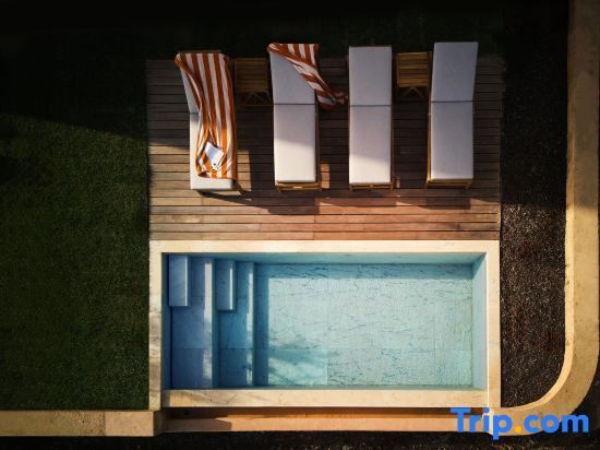 Draufsicht auf einen Pool mit Holzdeck, vier Liegestühlen und orange gestreiften Handtüchern.