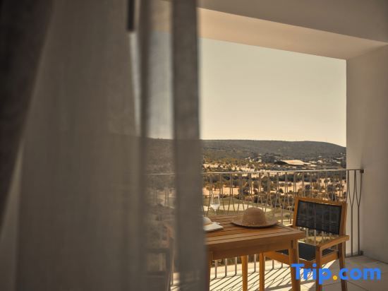 Balkon mit Holztisch und Stuhl sowie Blick auf die umliegende Hügellandschaft
