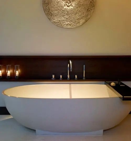 Freistehende Badewanne mit Kerzendekoration und kunstvoller Wandverzierung
