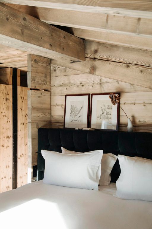Schlafzimmer mit Holzelementen, weißer Bettwäsche und gerahmter Kunst an der Wand.