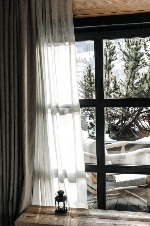 Schneebedeckte Landschaft durch das Fenster mit Vorhängen