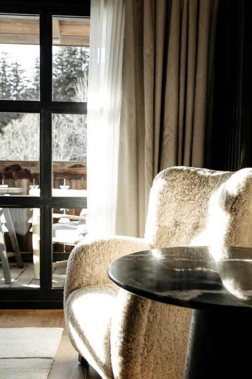 Sonniger Sitzbereich mit Kuschelsessel und Blick auf Terrasse und Wald.