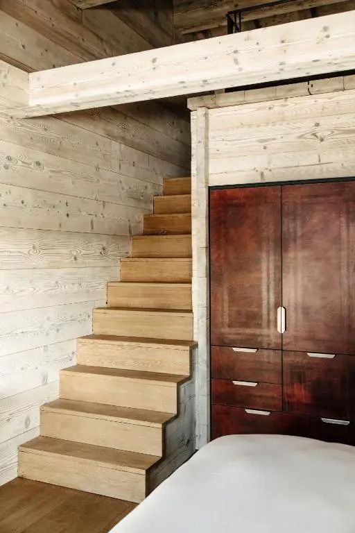 Holztreppe neben einem dunklen Kleiderschrank im Dachboden eines Hotelzimmers