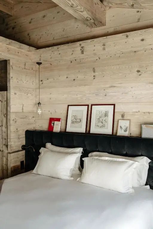 Modernes Bett mit künstlerischen Akzenten und Holzverkleidung im Hotelzimmer