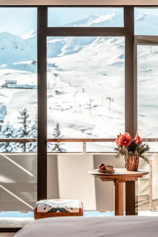 Balkon mit Tisch und Blumen vor schneebedeckter Landschaft