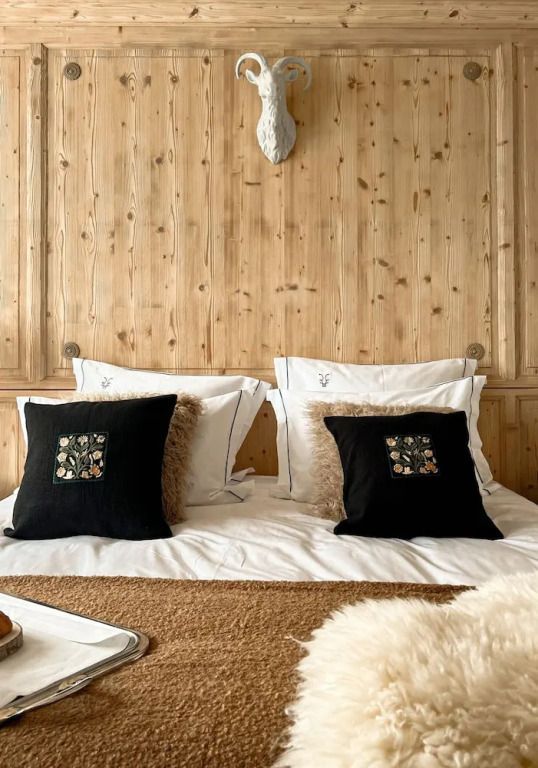 Holzverkleidetes Zimmer mit stilvollen Kissen auf dem Bett