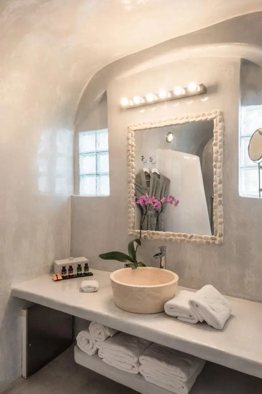 Elegant eingerichtetes Badezimmer mit Steinwaschbecken und beleuchtetem Spiegel