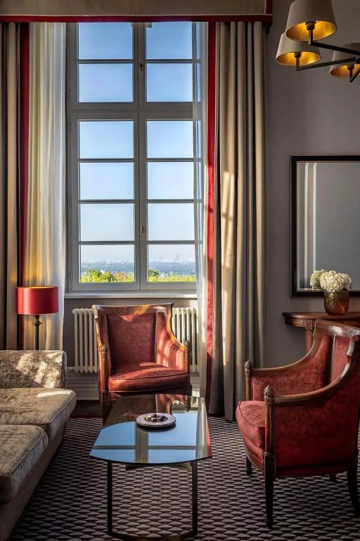 Wohnbereich der Suite mit Sesseln und Sofa sowie Blick durch das Fenster auf die Landschaft.