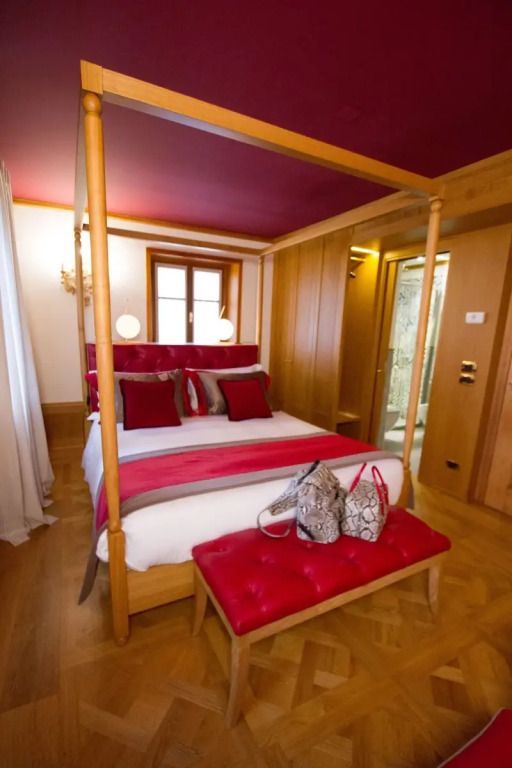 Helles Doppelzimmer mit rotem Polsterbett und modernen Annehmlichkeiten.