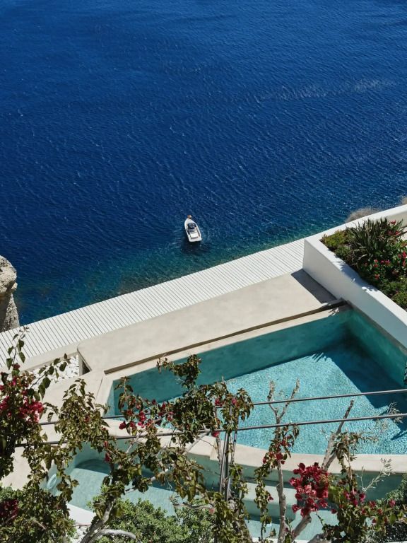 Infinity-Pool mit Blick auf das tiefe Blau des Meeres und kleine Yacht