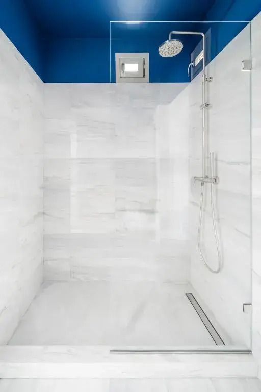 Marmorierte Dusche mit Glasabtrennung und blauem Akzent