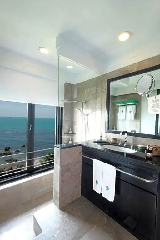 Modernes Badezimmer mit Meerblick, großer Spiegel und eleganter Einrichtung.
