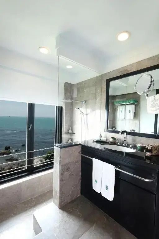 Modernes Badezimmer mit Meerblick, Dusche und großem Spiegel, hochwertige Einrichtung.
