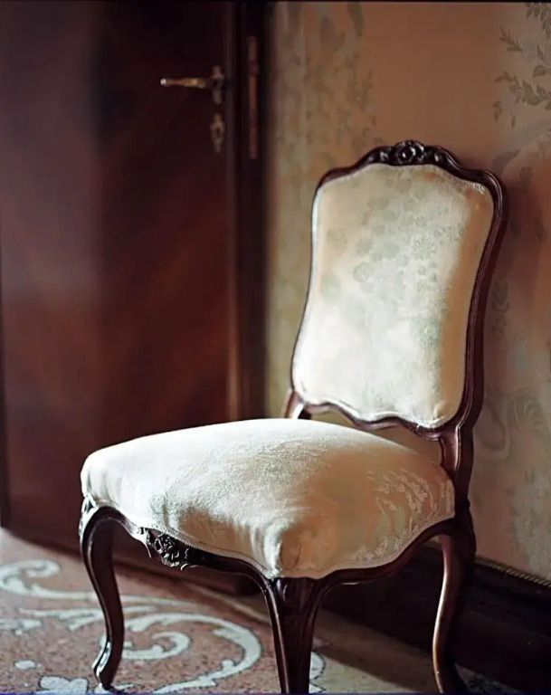 Eleganter antiker Stuhl vor Holztür in der Suite