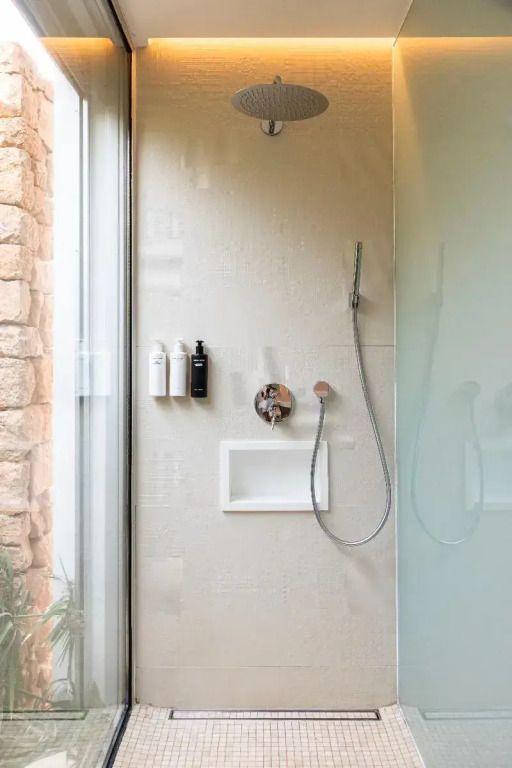 Moderne Dusche mit Glaswand und Pflegeprodukte-Spendern in einem eleganten Badezimmer
