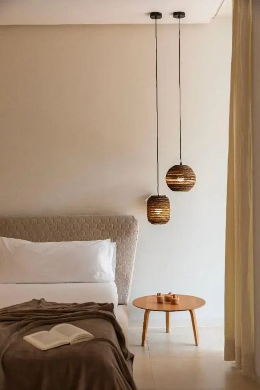 Gemütliches Schlafzimmer mit modernem Bett und zwei hängenden Holzlampen